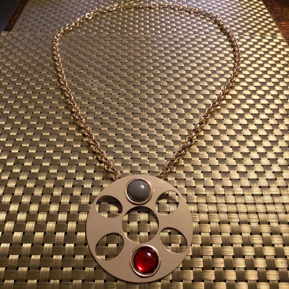 Long necklace with gold pendant with red and gray stones and cutouts